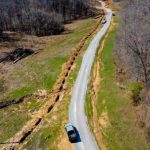 aerial view of gravel road with trench dugged next to it.