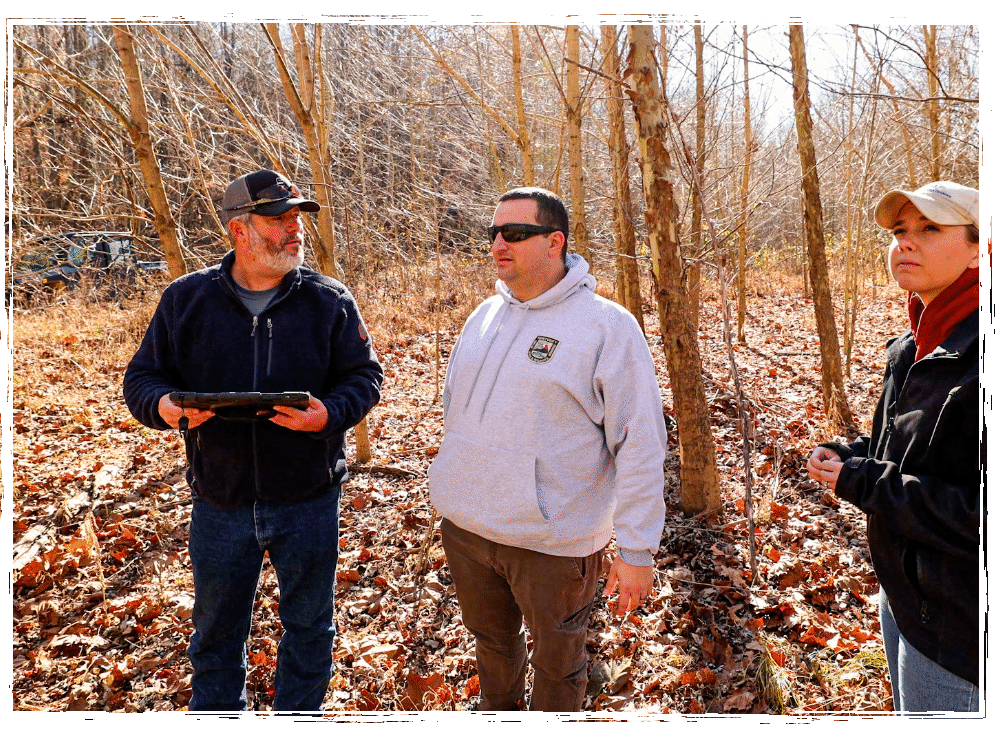 2 men and 1 woman in woods discussing project